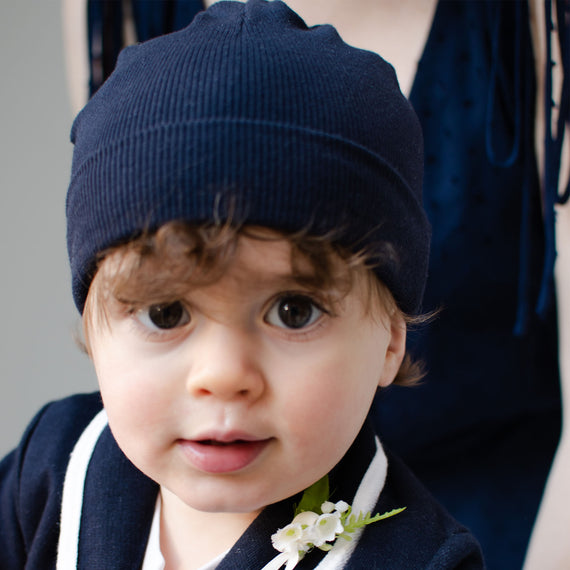 Photo of a baby boy wearing the navy Ribbed Pima Beanie made from 100% ribbed textured Pima cotton.