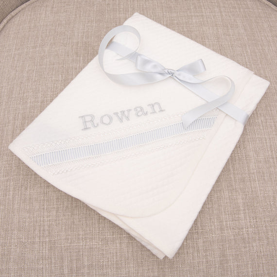 A personalized boys baptism blanket embroidered with the name Rowan in silk.