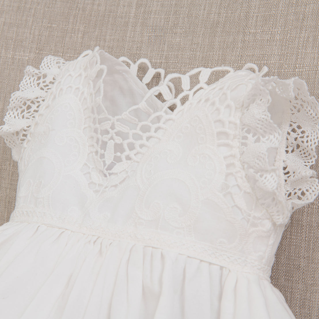 Close-up detail of the scalloped edge cotton lace of the lily christening romper dress bodice top