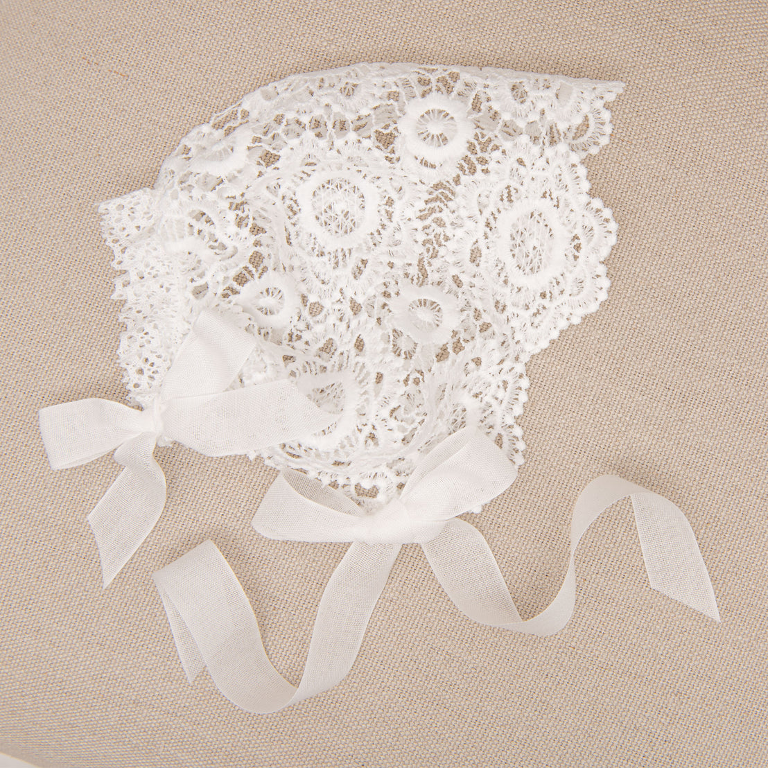 Poppy lace christening bonnet photographed on top of a chair.