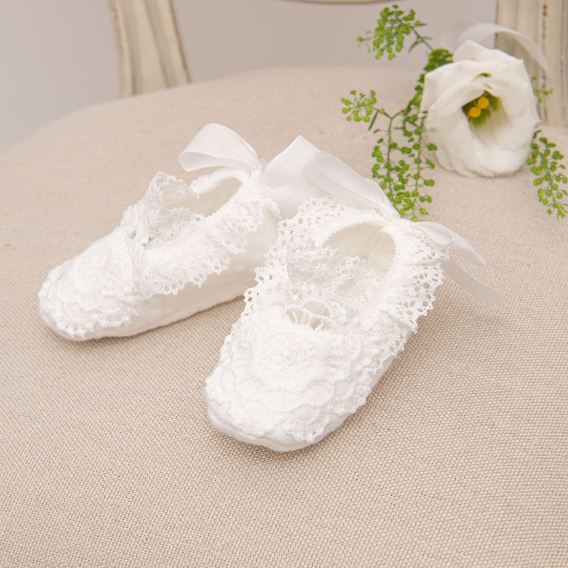 Close up detail of lace christening booties photographed in profile. 