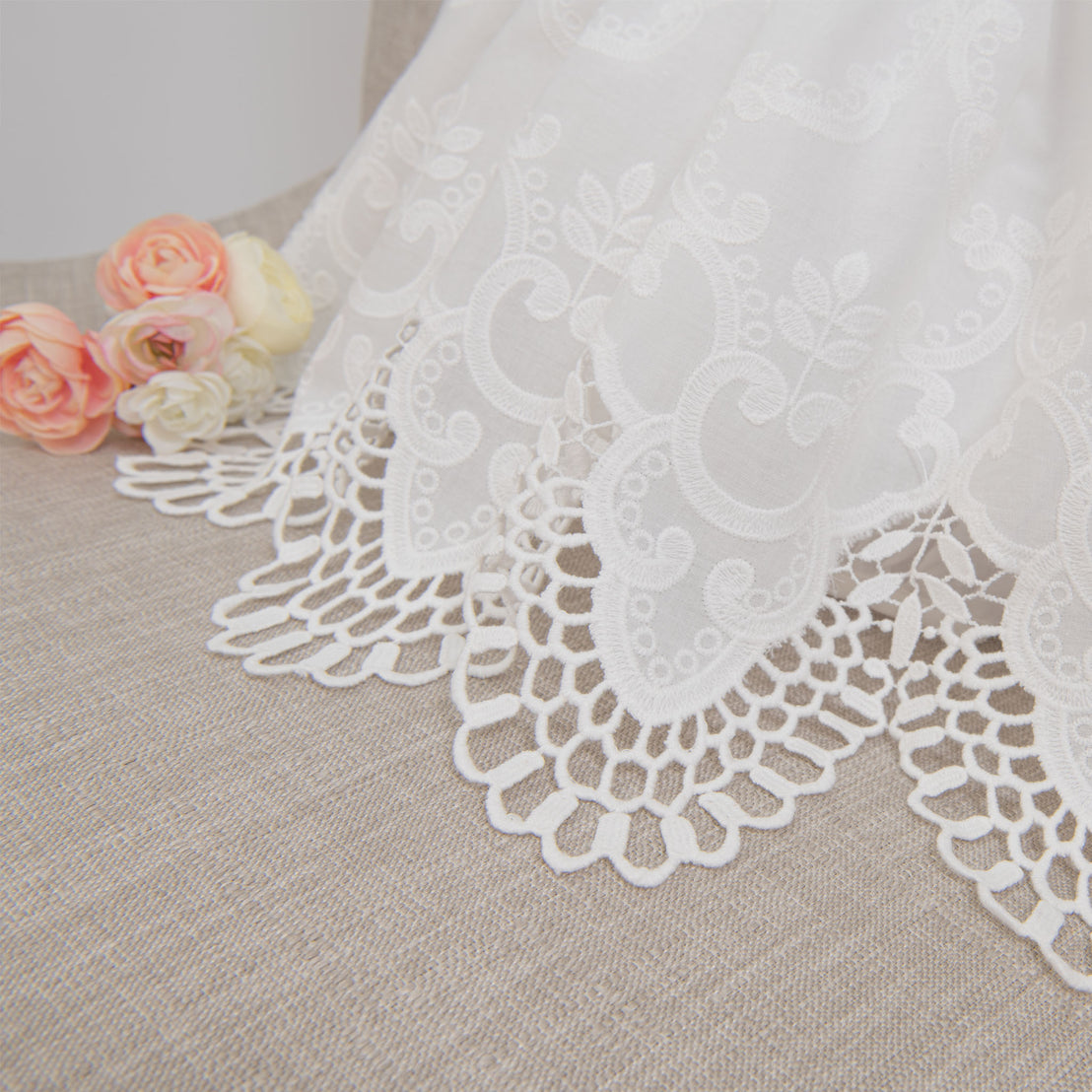 Close-up detail of the scalloped edge cotton lace of the lily christening romper dress skirt
