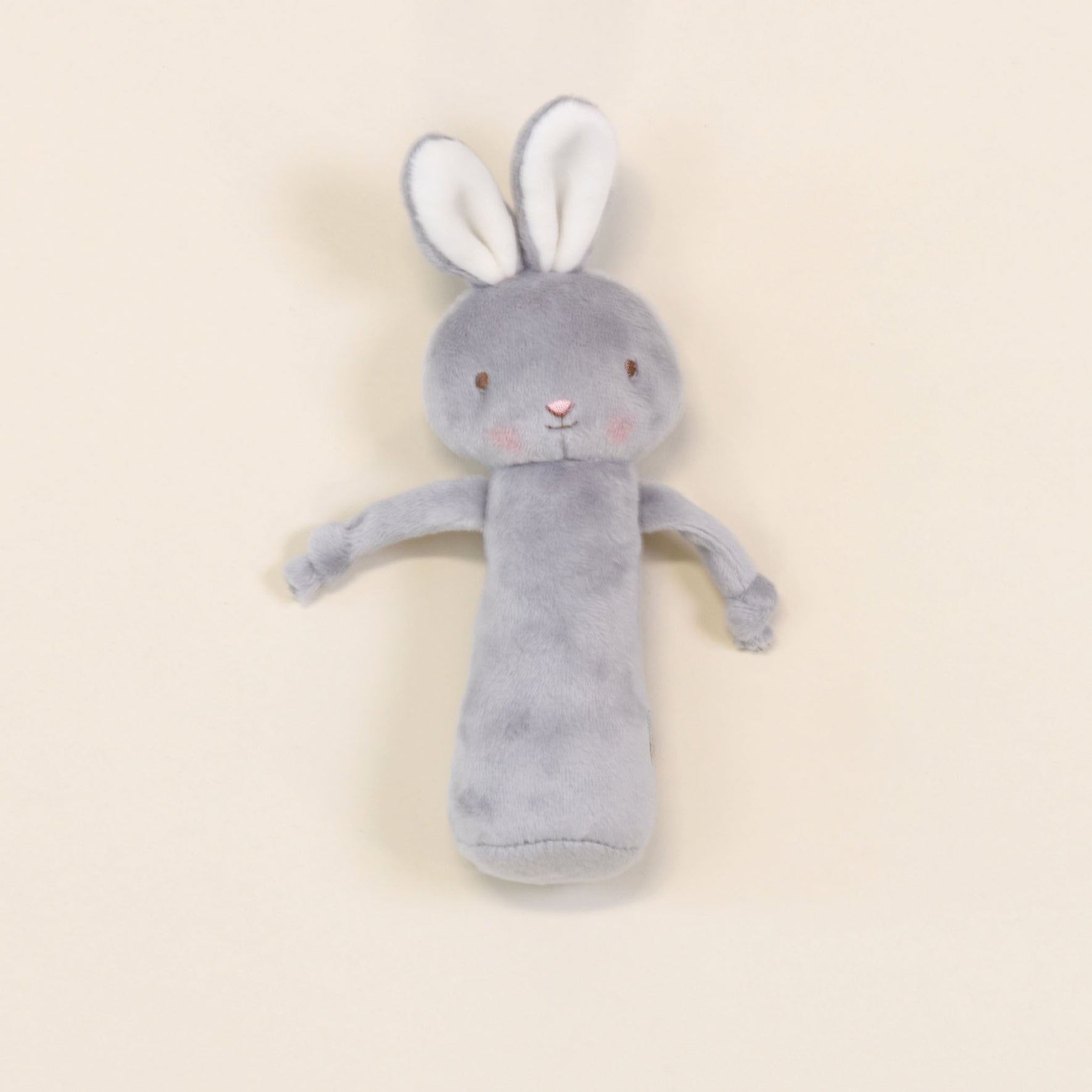 The Friendly Chime Rattle is a cozy, gray plush rabbit toy featuring long ears and delicate embroidered details. Its uncomplicated face and soft pink cheeks lie against a light beige backdrop, making it both a comforting companion and a velour chime rattle that’s perfectly safe for babies to cuddle endlessly.