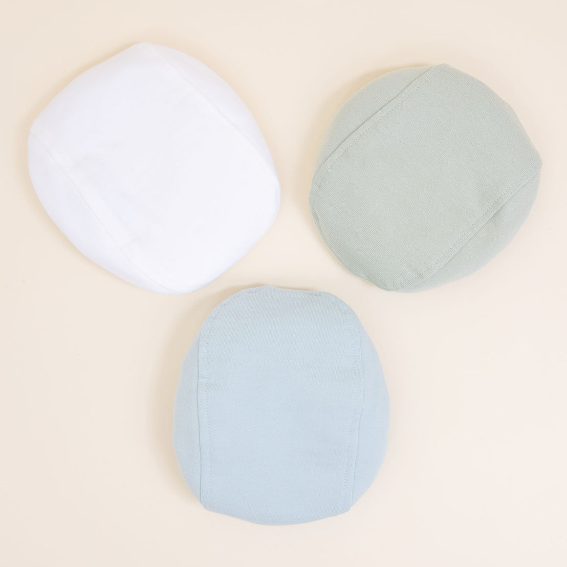 Flat lay photo of the the three Theodore Newsboy Caps in blue, green, and white.