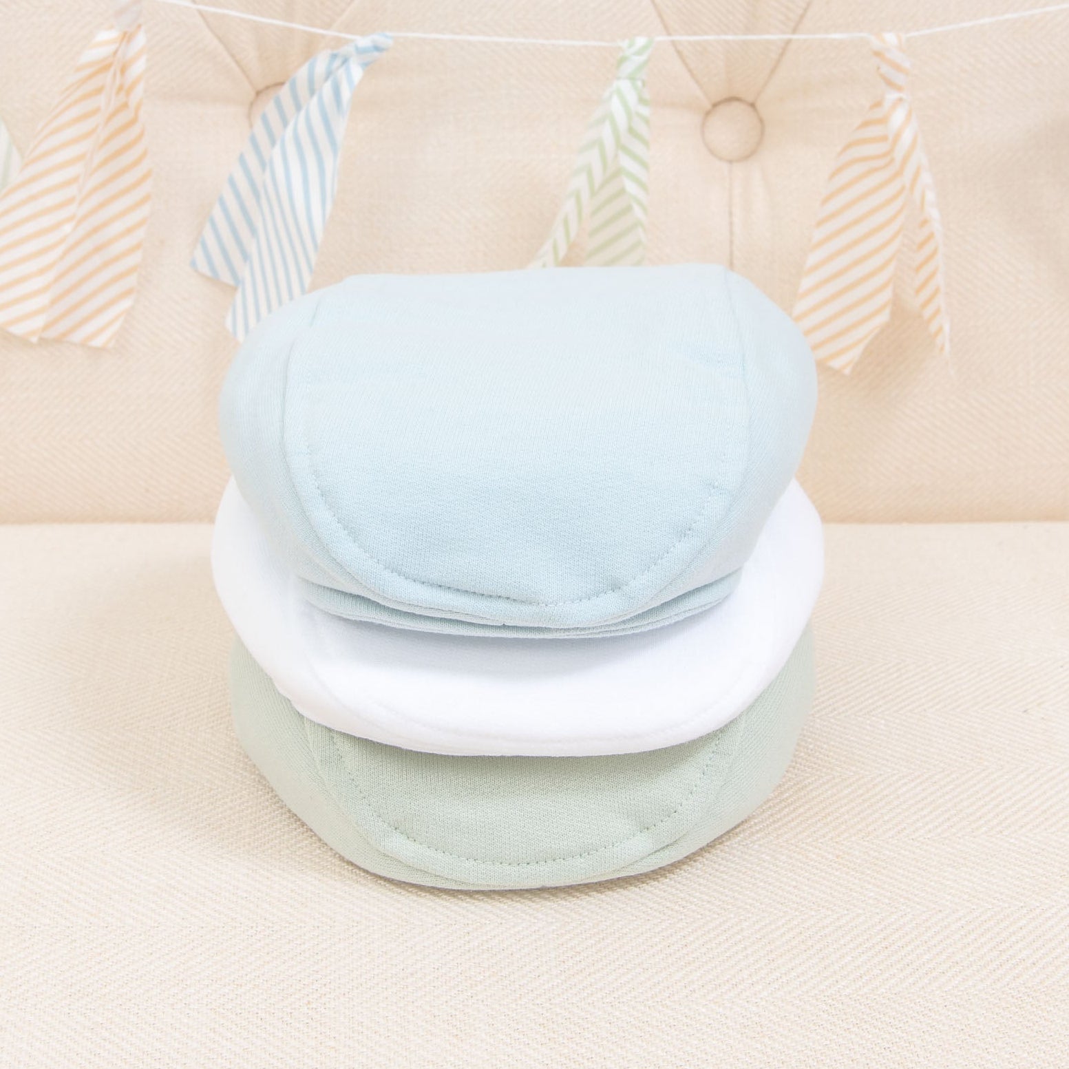 Flat lay photo of the the three Theodore Newsboy Caps in blue, green, and white.