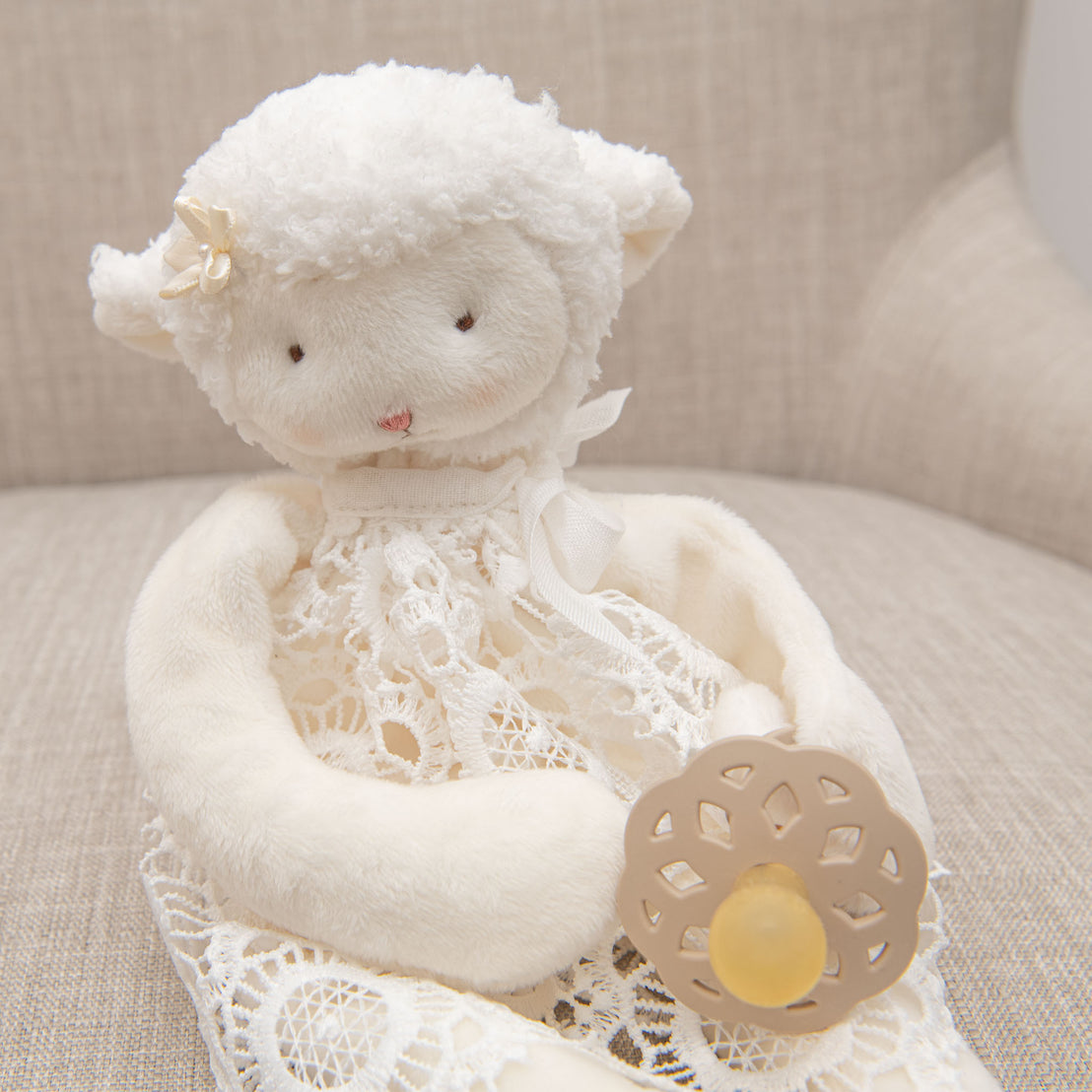 Baby lamb doll holding baby pacifier.