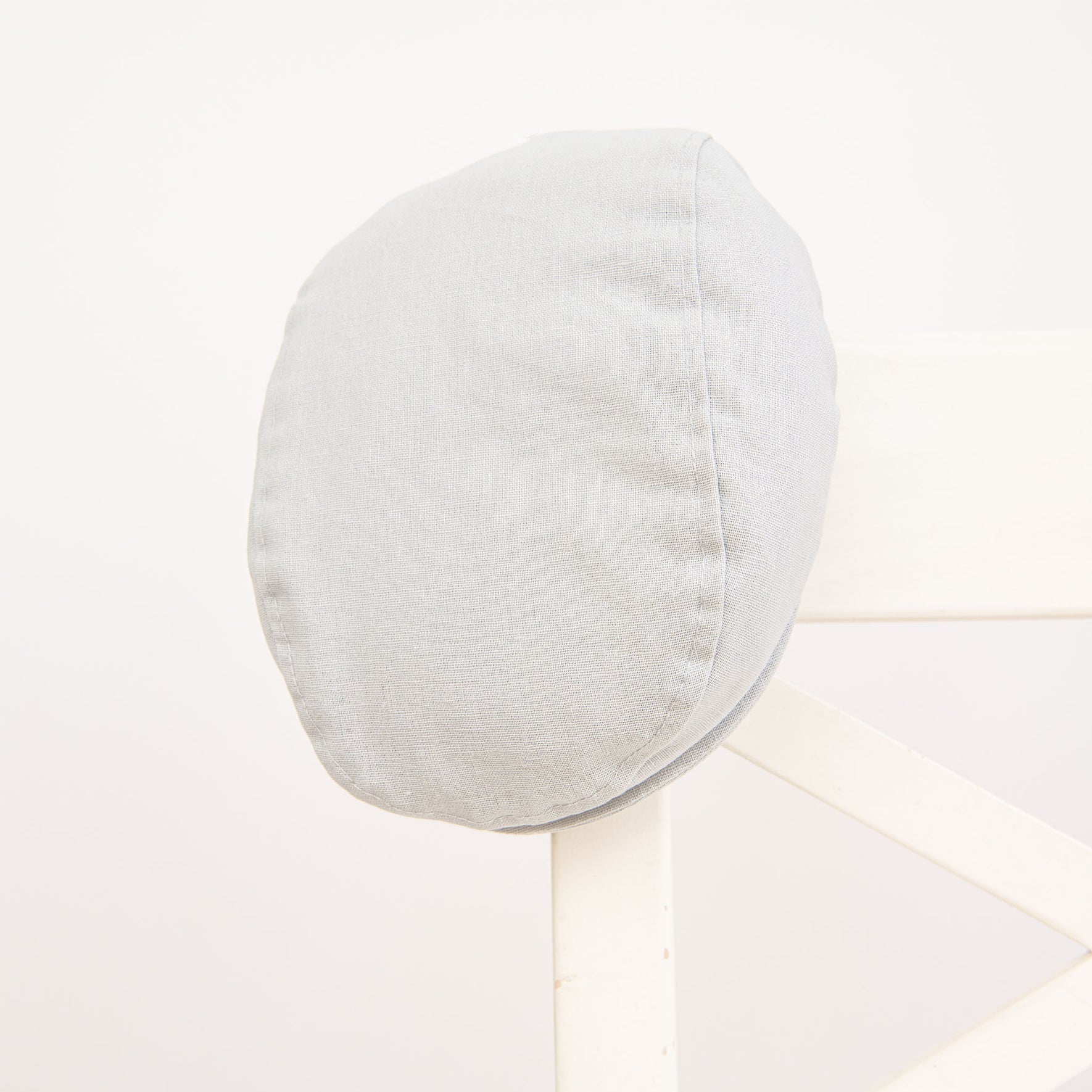 Flat lay photo of the Grayson Linen Newsboy Cap. The hat is made from a linen/cotton blend in grey with a soft elastic band around the back.