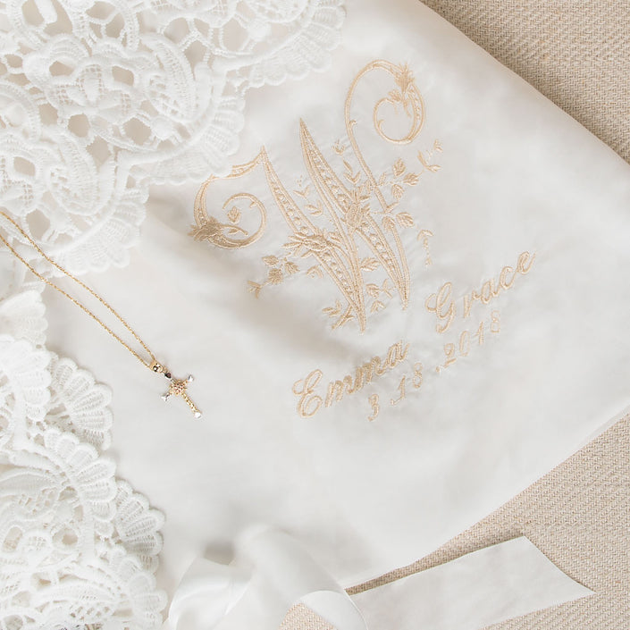 Close-up of the embroidered monogram on the Lola Christening Gown, featuring an elegant 'W' initial, with the name 'Emma Grace' and the date '3-13-2018,' showcasing christening personalization options.