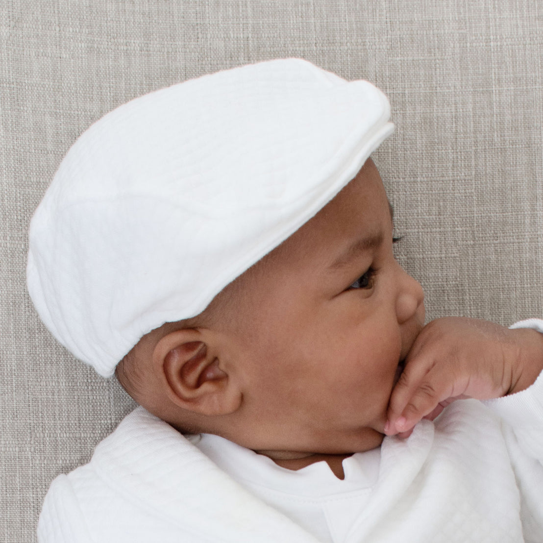 Baby boy wearing the Elijah Newsboy Cap. The photo shows the side view of the Newsboy Cap showing the soft elastic that ensures a nice, comfortable fit
