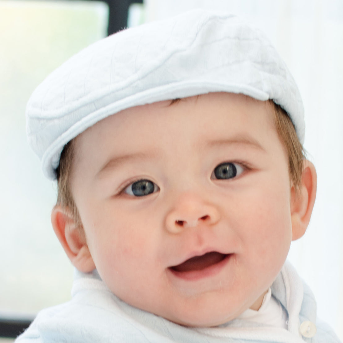 Baby boy smiling and wearing the Logan Newsboy Cap.