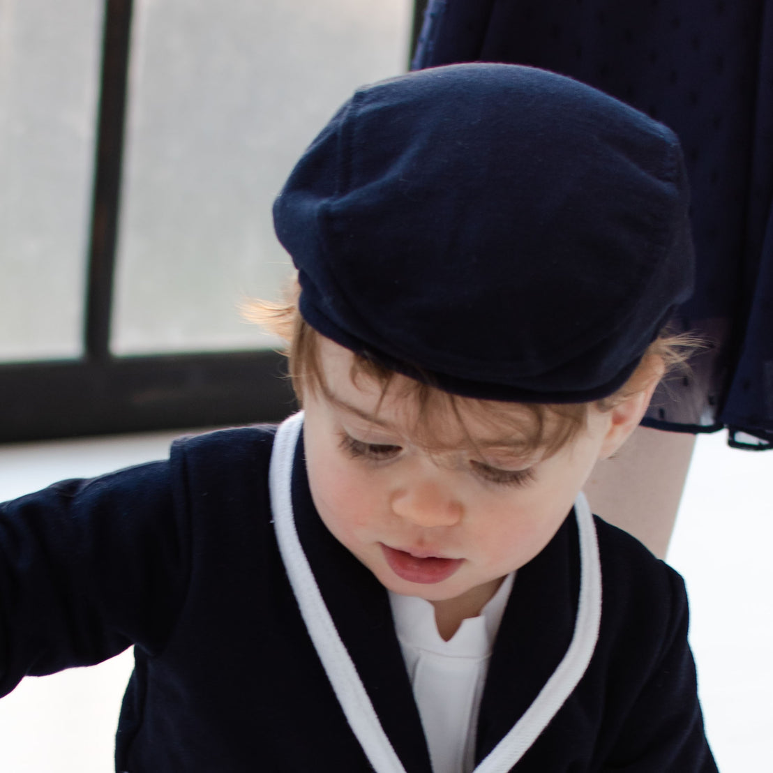 Closeup photo of a baby boy wearing the navy Elliott Newsboy Cap.