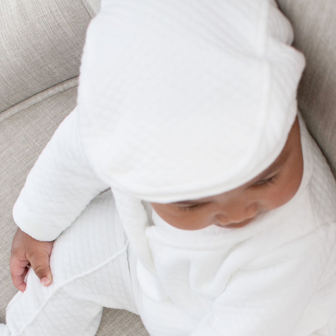 Baby boy wearing the Elijah Newsboy Cap. The photo shows the top of the hat and the white textured cotton that it is crafted from