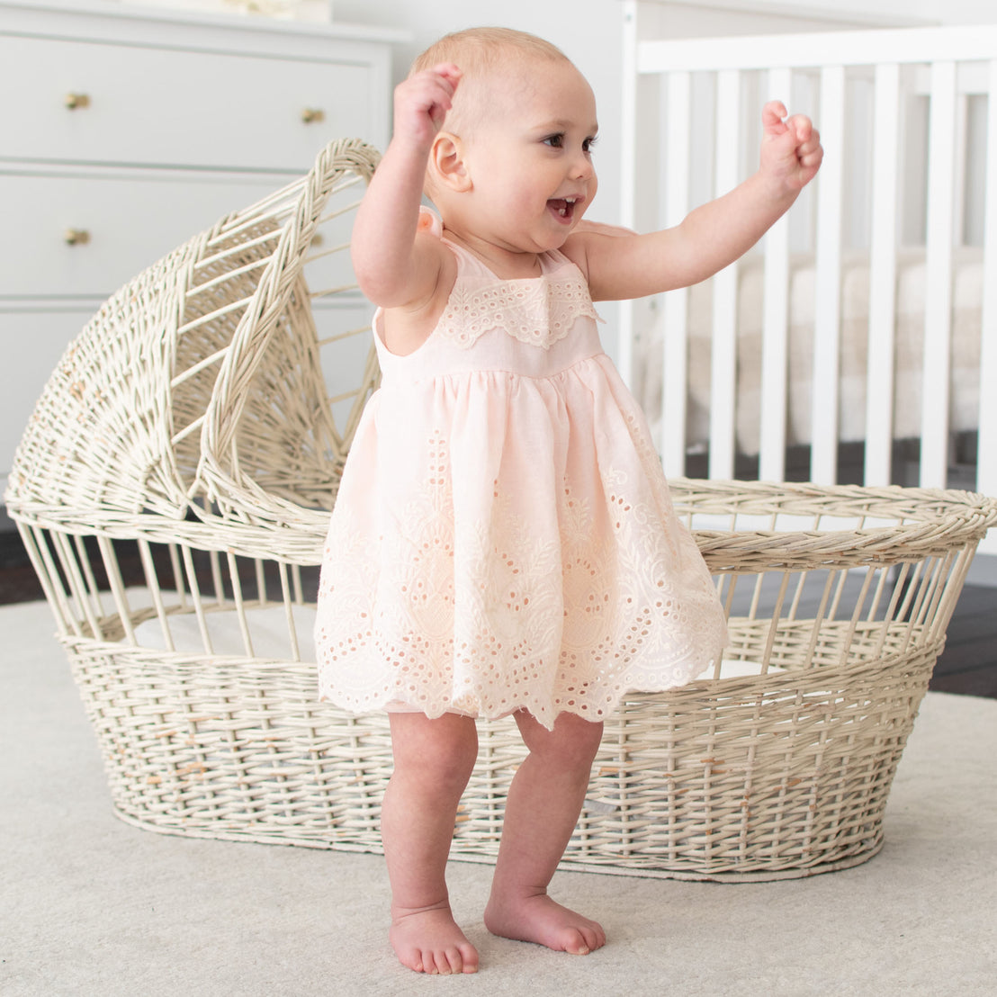 Baby wearing the pink Ingrid Romper Dress that is handcrafted with a lightweight 100% cotton 