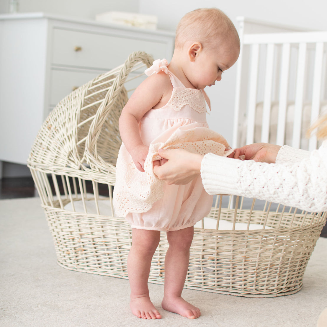 Baby wearing the pink Ingrid Romper Dress. The photo showcases the super soft gauze cotton lining that fits like a jumpsuit with snaps along the inside leg 