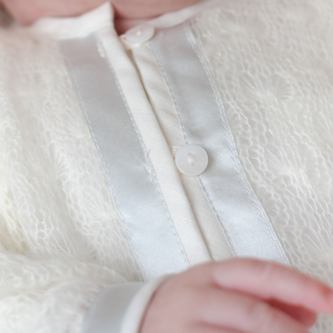 Close up detail of the Owen Knit Sweater buttons and ivory linen and blue silk ribbon trim