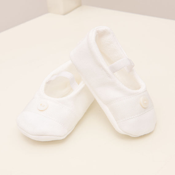 Flat lay photo of the Asher Booties made in a 100% White french terry cotton with a soft elastic strap and featuring a white grosgrain ribbon with a button detail on the top.