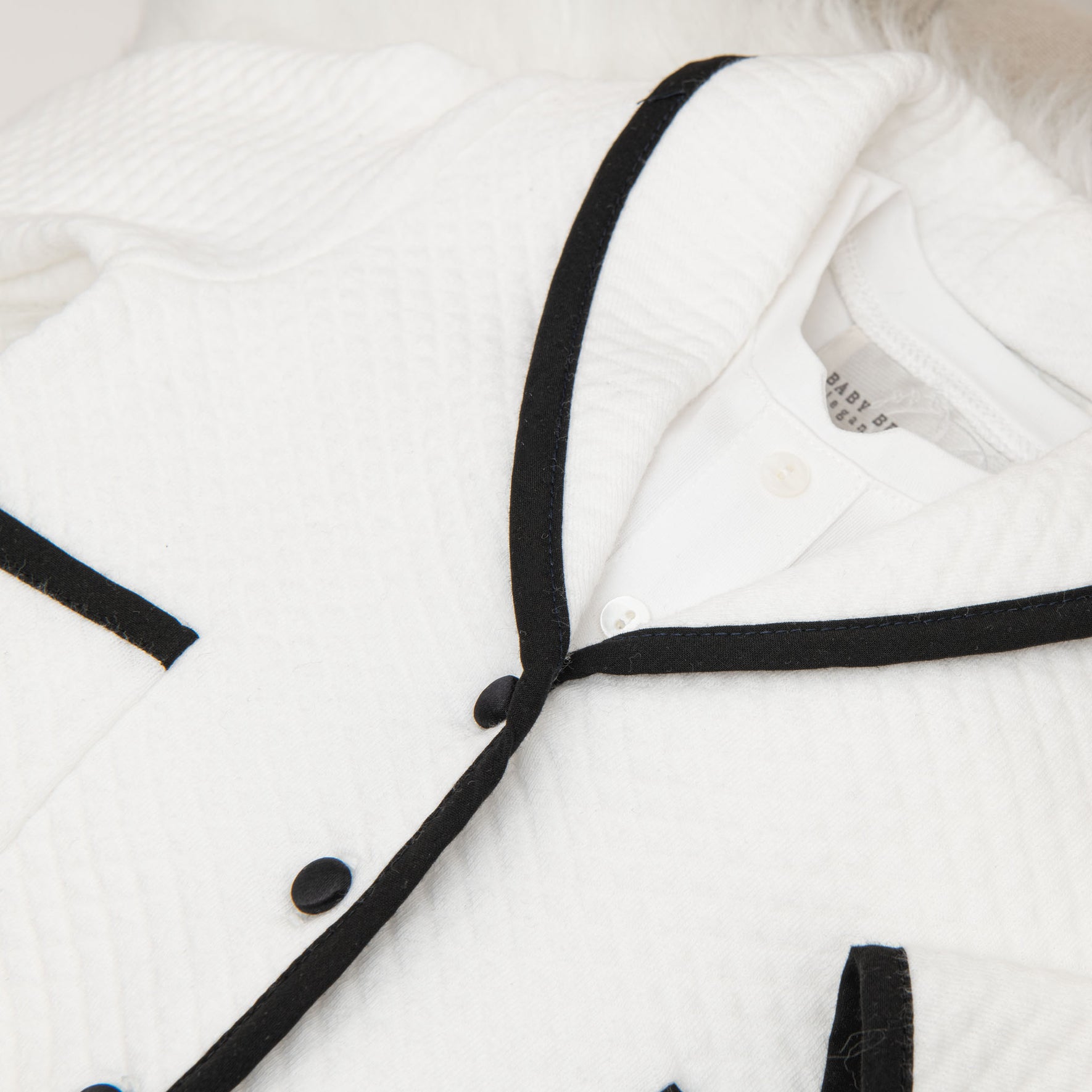 A close-up of the jacket from the James 3-Piece Suit, showing the fine quilted texture, black trim, and brand label inside the collar.