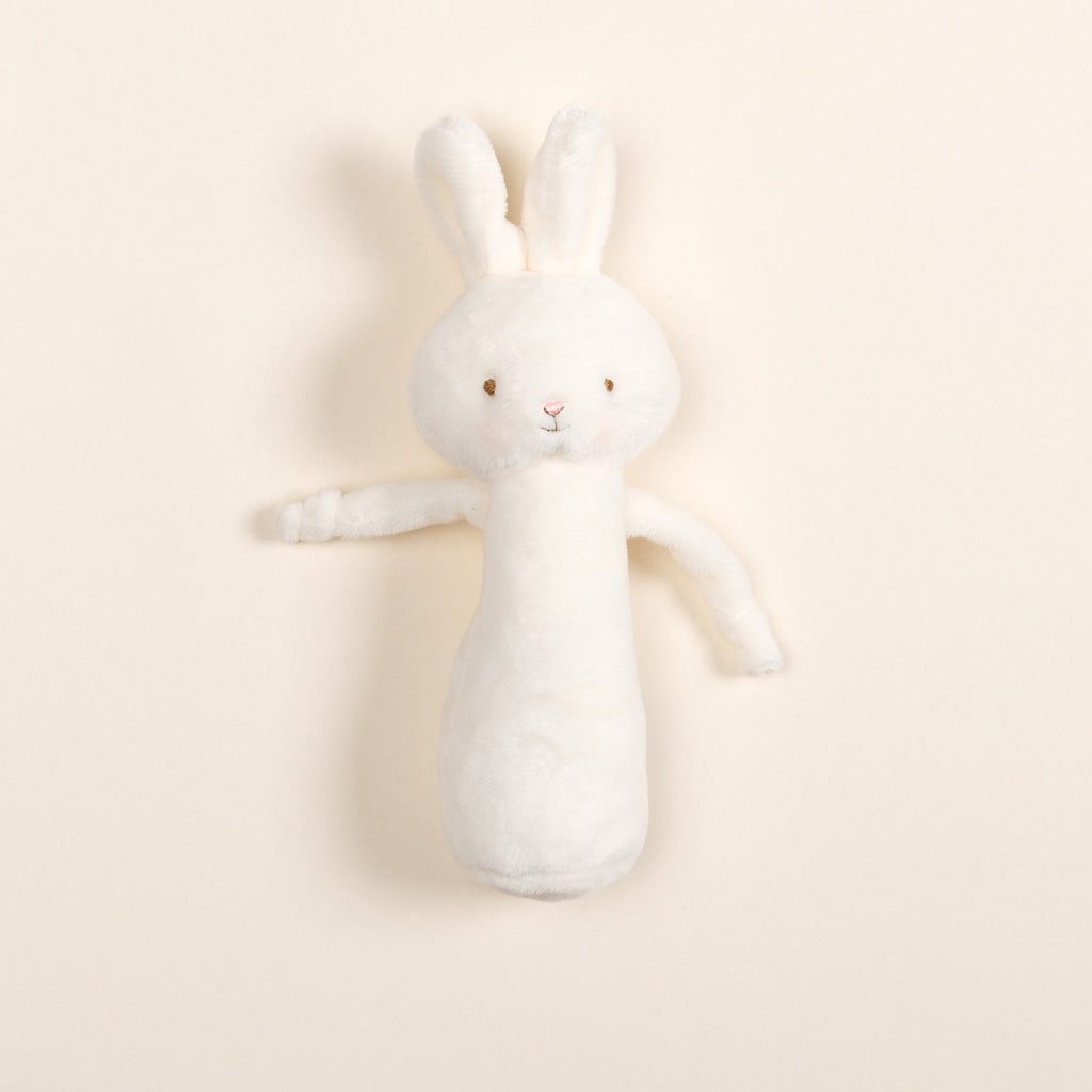 Introducing the Friendly Chime Rattle, a gentle velour plush toy designed as a rabbit with soft white fur, long ears, and intricate embroidered facial features. This baby-safe chime rattle rests on a light beige background, perfect for delighting little ones.