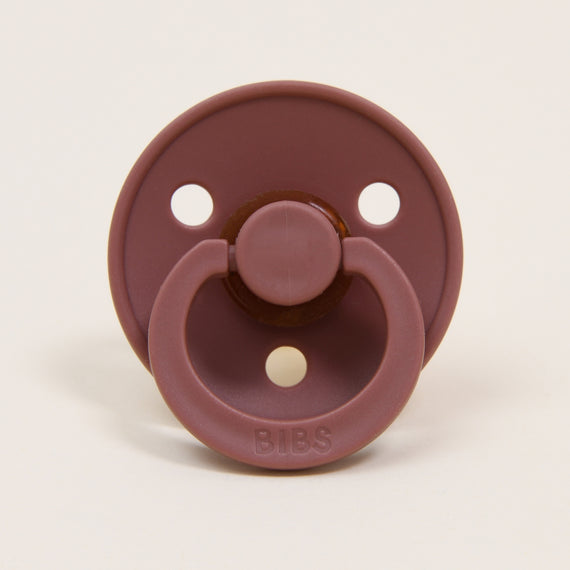 A Bibs Pacifier from the Woodchuck 2 Pack, crafted with natural rubber, is showcased against a plain background. Originating from Denmark, it features three ventilation holes, a round shield, and a pull handle—perfect for helping babies self-soothe.