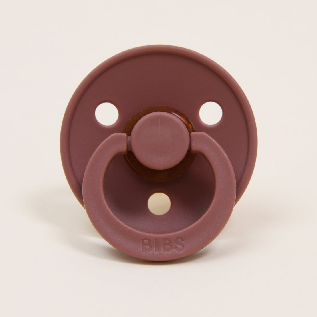 The Bibs Pacifier Set in Woodchuck & Ivory showcases a timeless and elegant design crafted from natural rubber. It features a round shield with three ventilation holes and a handle embossed with "BIBS," all in a muted brown color, making it ideal for helping little ones self-soothe.