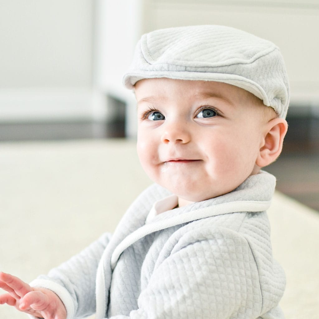 Baby boy smiling in Asher newsboy cap and suit jacket. 