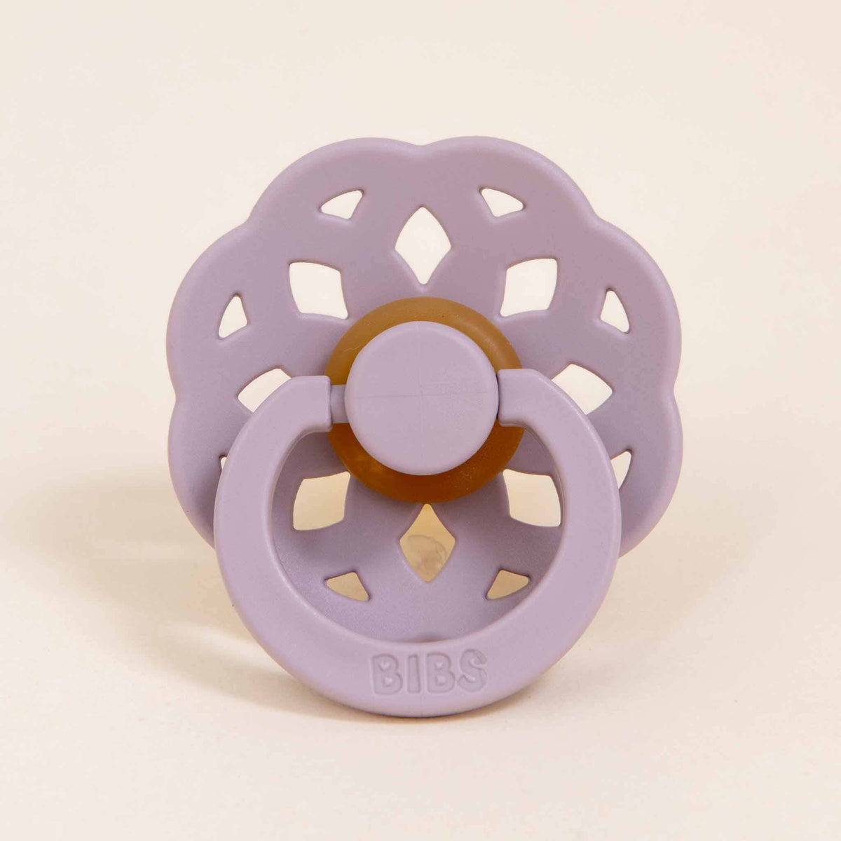 The Bibs Lace Pacifier in Dusky Lilac is beautifully crafted with a bohemian flair, showcasing a flower-shaped shield and a natural brown rubber nipple, providing babies with a stylish self-soothing option. The handle elegantly features the embossed word "BIBS," marrying function with fashion.