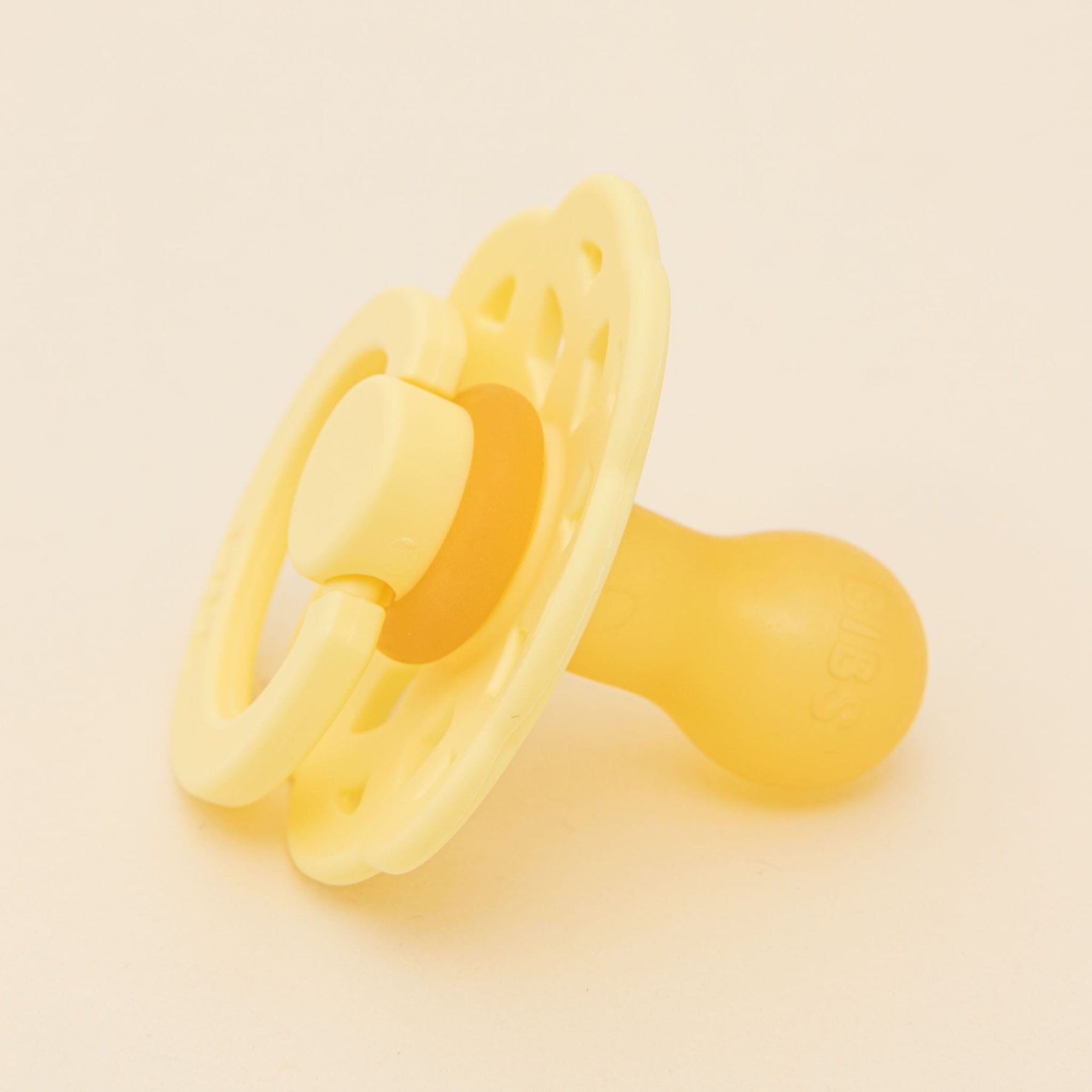 The Bibs Lace Pacifier 2 Pack in Sunshine features a yellow natural rubber pacifier with a circular shield and round nipple, resting on a plain light background and highlighting its bohemian-inspired design ideal for assisting babies in self-soothing.