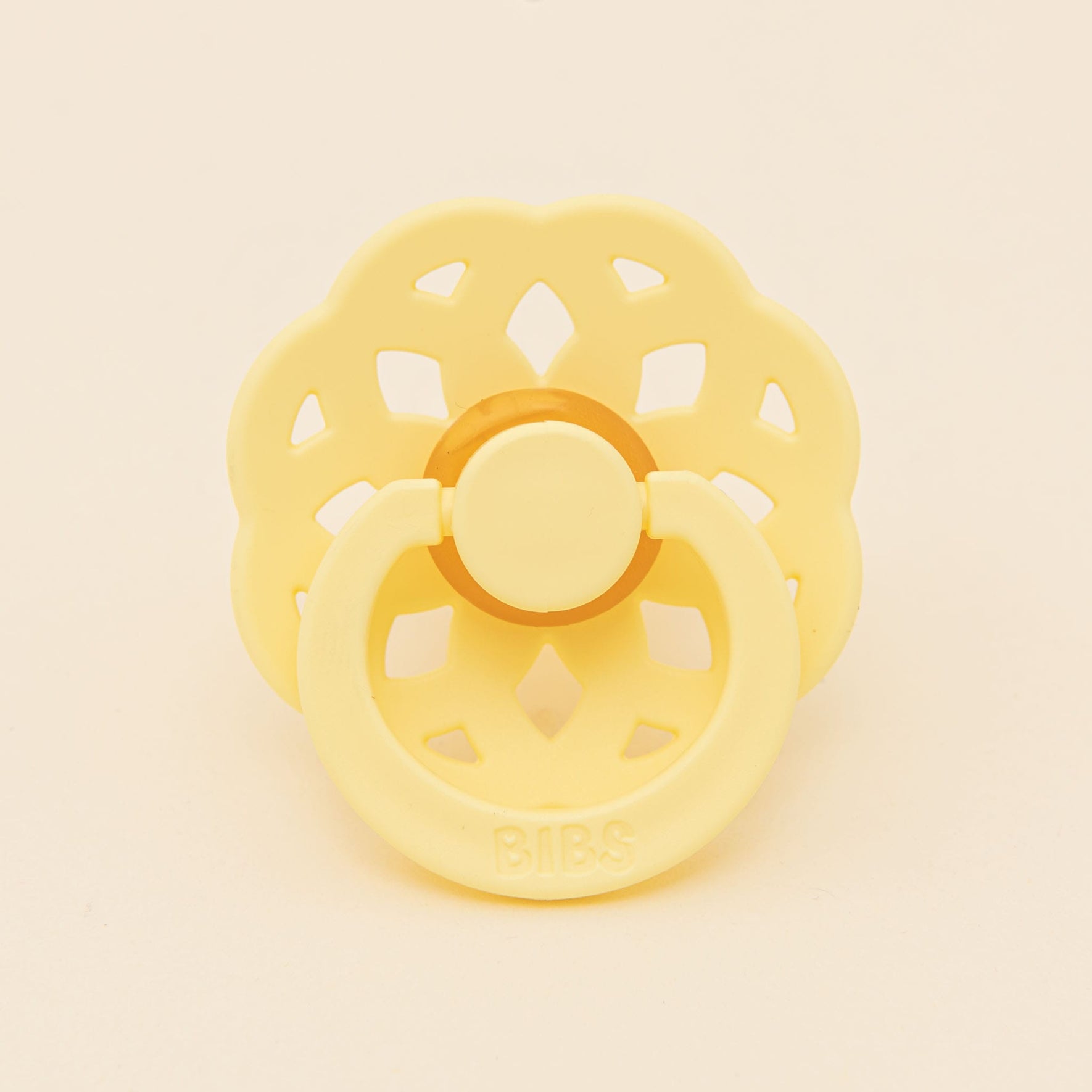 The Bibs Lace Pacifier 2 Pack in Sunshine boasts a bohemian-inspired design with a flower-shaped shield and circular handle, all crafted from natural rubber set against a plain background.
