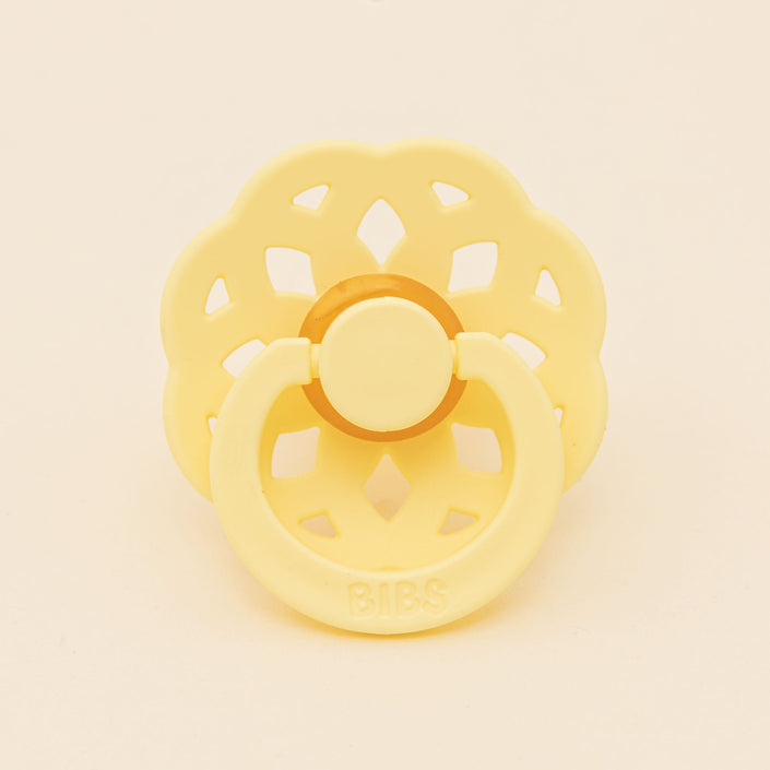 The Bibs Lace Pacifier 2 Pack in Sunshine boasts a bohemian-inspired design with a flower-shaped shield and circular handle, all crafted from natural rubber set against a plain background.