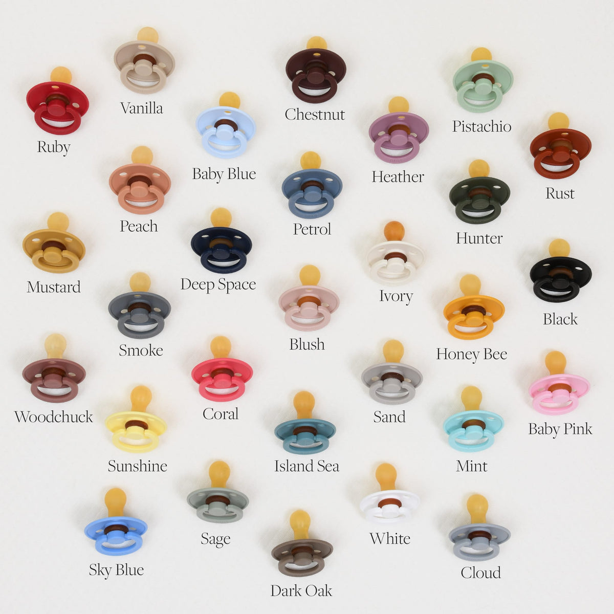 A grid display showcases a variety of Bibs Pacifiers made from natural rubber, set against a white backdrop. Each row presents pacifiers in distinct colors with labels like Vanilla, Pistachio, Blush, Black, Mint, and others. These pacifiers are expertly crafted in Denmark to provide the ultimate self-soothe experience. The collection includes a total of 30 pacifiers.