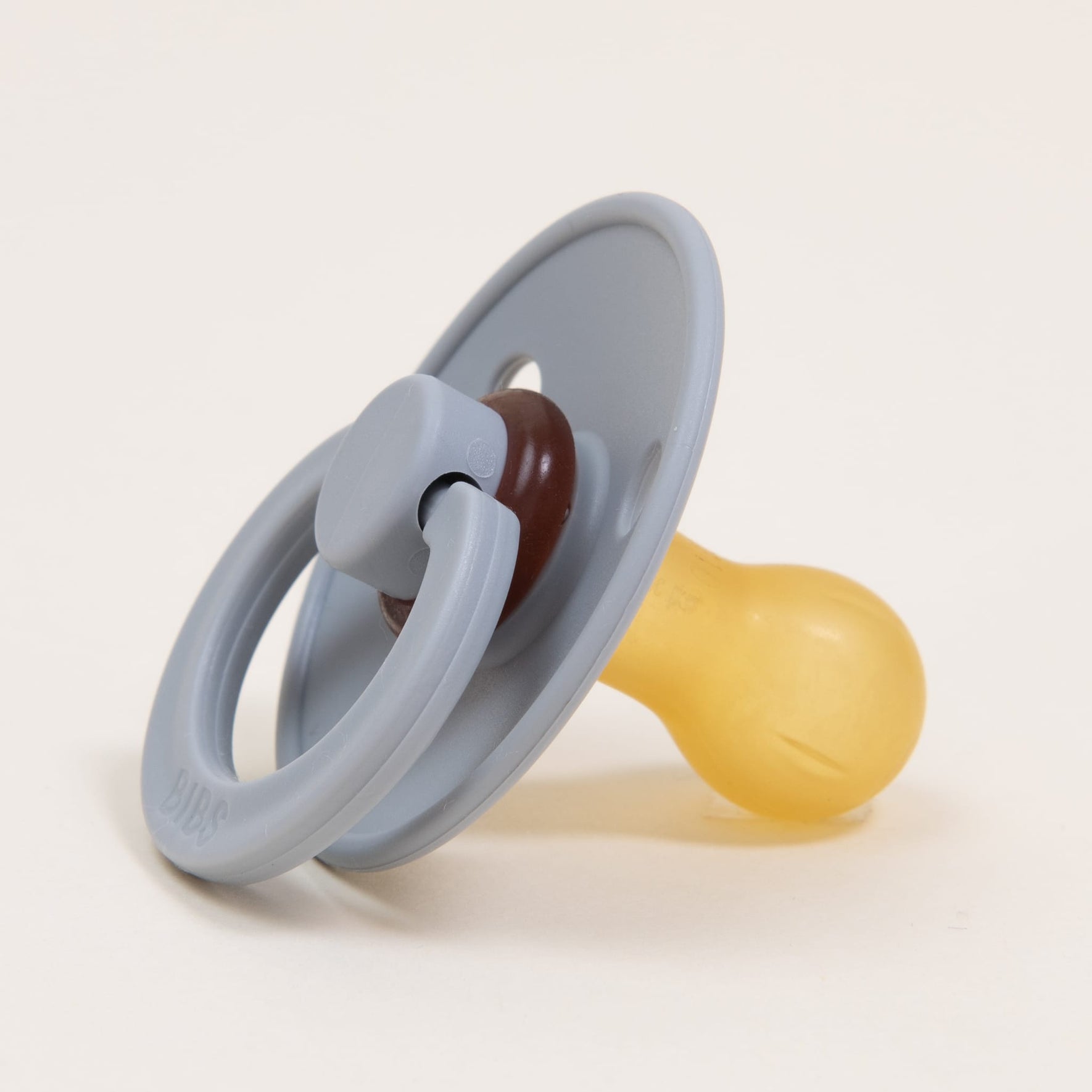 A Bibs Pacifier 2 Pack | Cloud, featuring a natural rubber nipple and a round handle in a gray and yellow design, is elegantly displayed on a plain white background. Perfect for infants in Denmark who need to self-soothe.