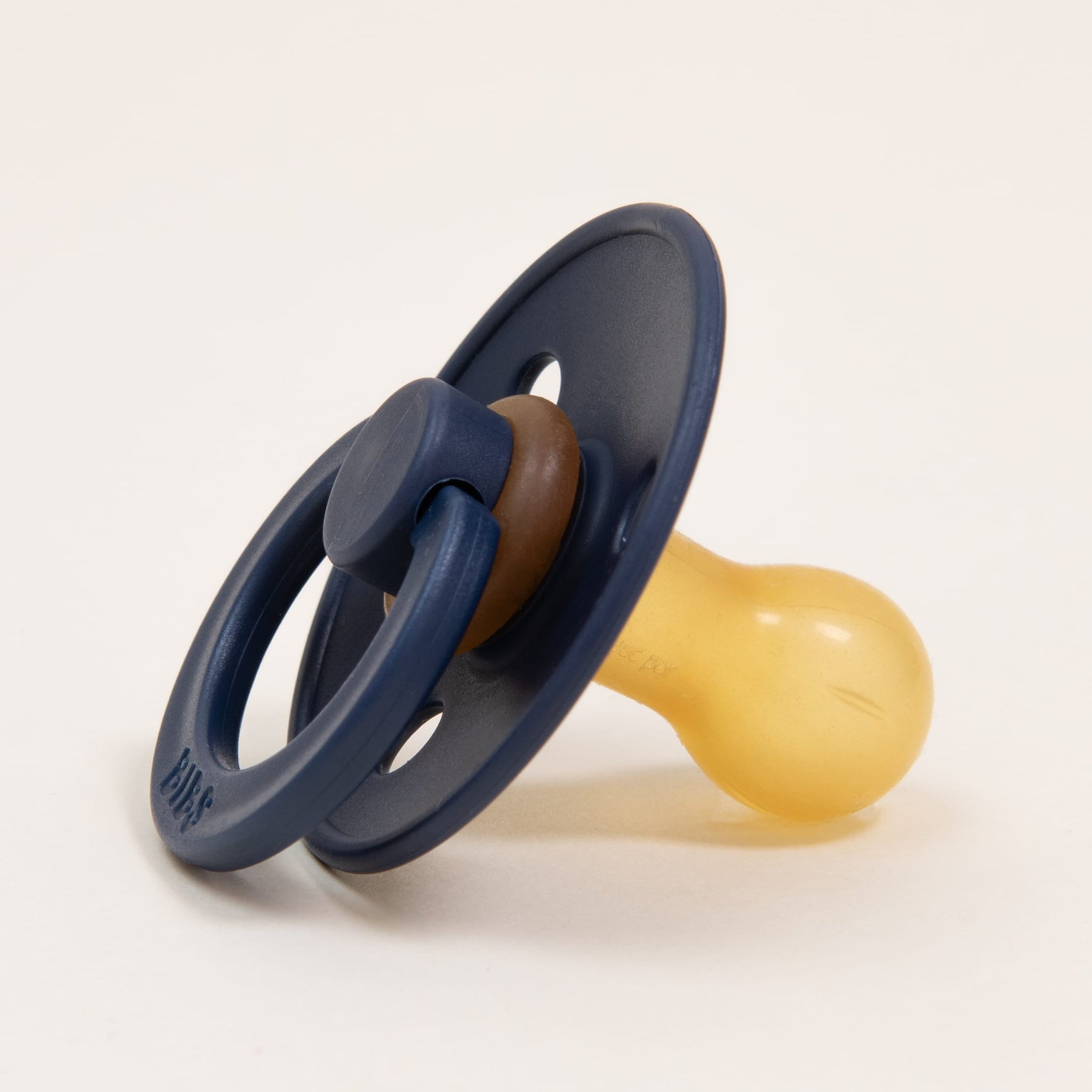 A Bibs Pacifier from the Deep Space 2 Pack, with a soothing blue and yellow color scheme, is pictured on a simple light background. Crafted from natural rubber in Denmark, this pacifier includes a round, soft nipple and a circular shield featuring two holes and a handle, making it ideal for helping little ones self-soothe.