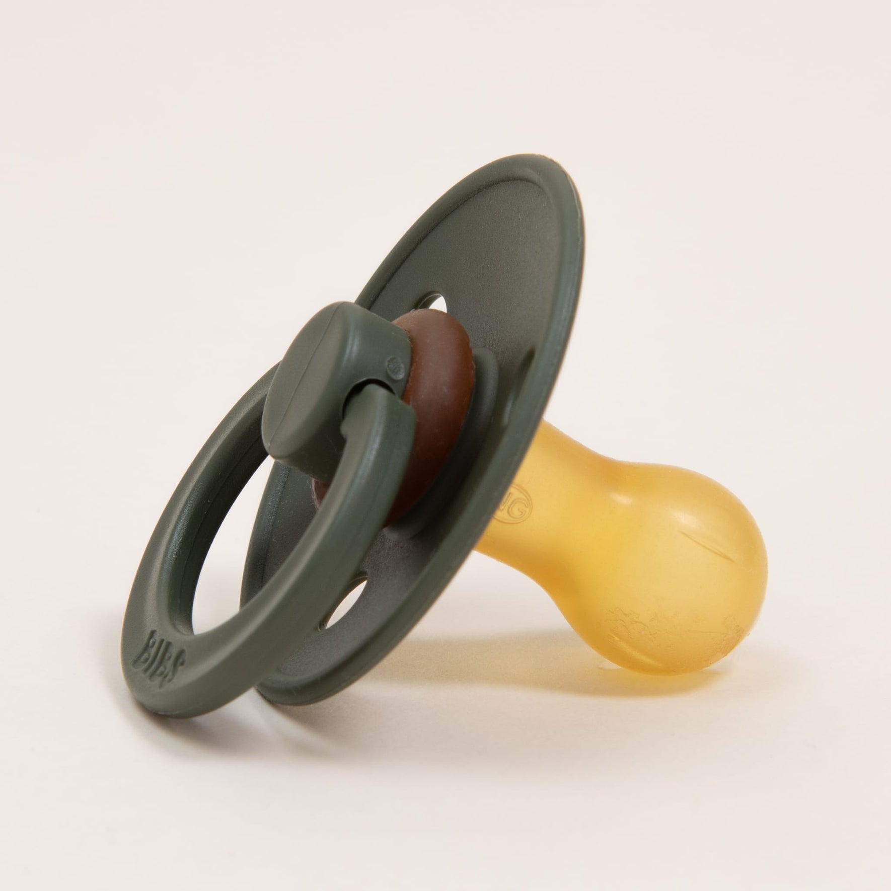 A Bibs Pacifier from the Hunter 2 Pack, featuring a green and brown color scheme with a round nipple made of natural rubber, creates a classic look as it lies against a plain white background.