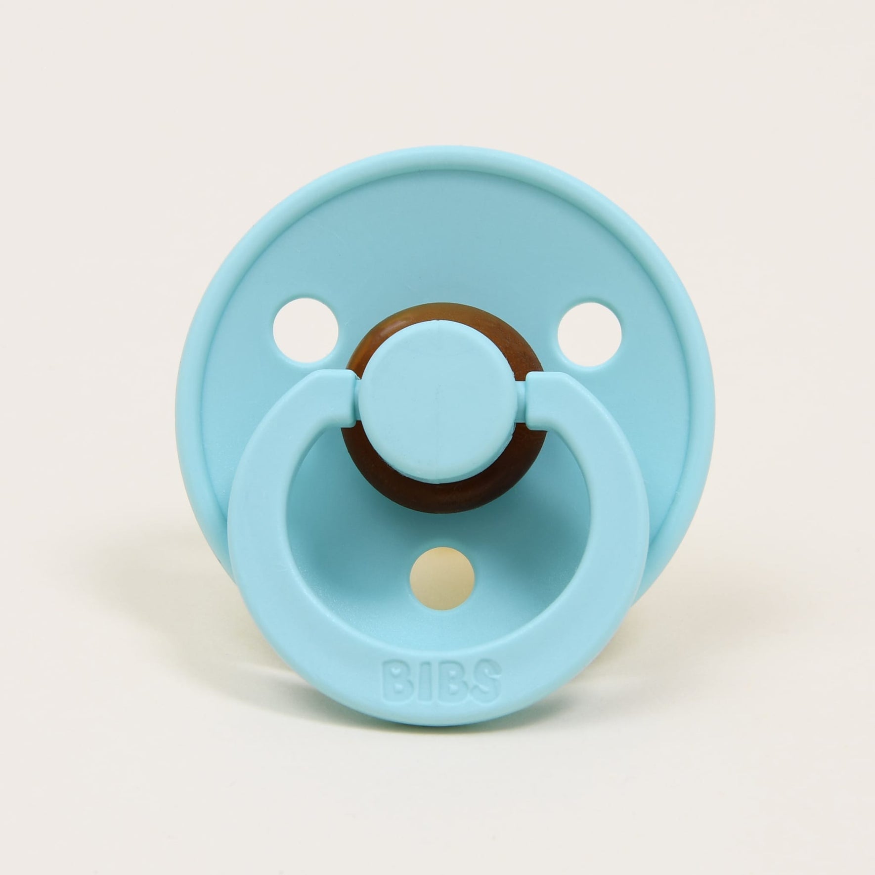 A mint pacifier with a circular shield featuring two holes, crafted from natural rubber to aid in soothing babies. The handle is embossed with the brand name "Bibs," which is renowned for its design and manufacturing in Denmark.