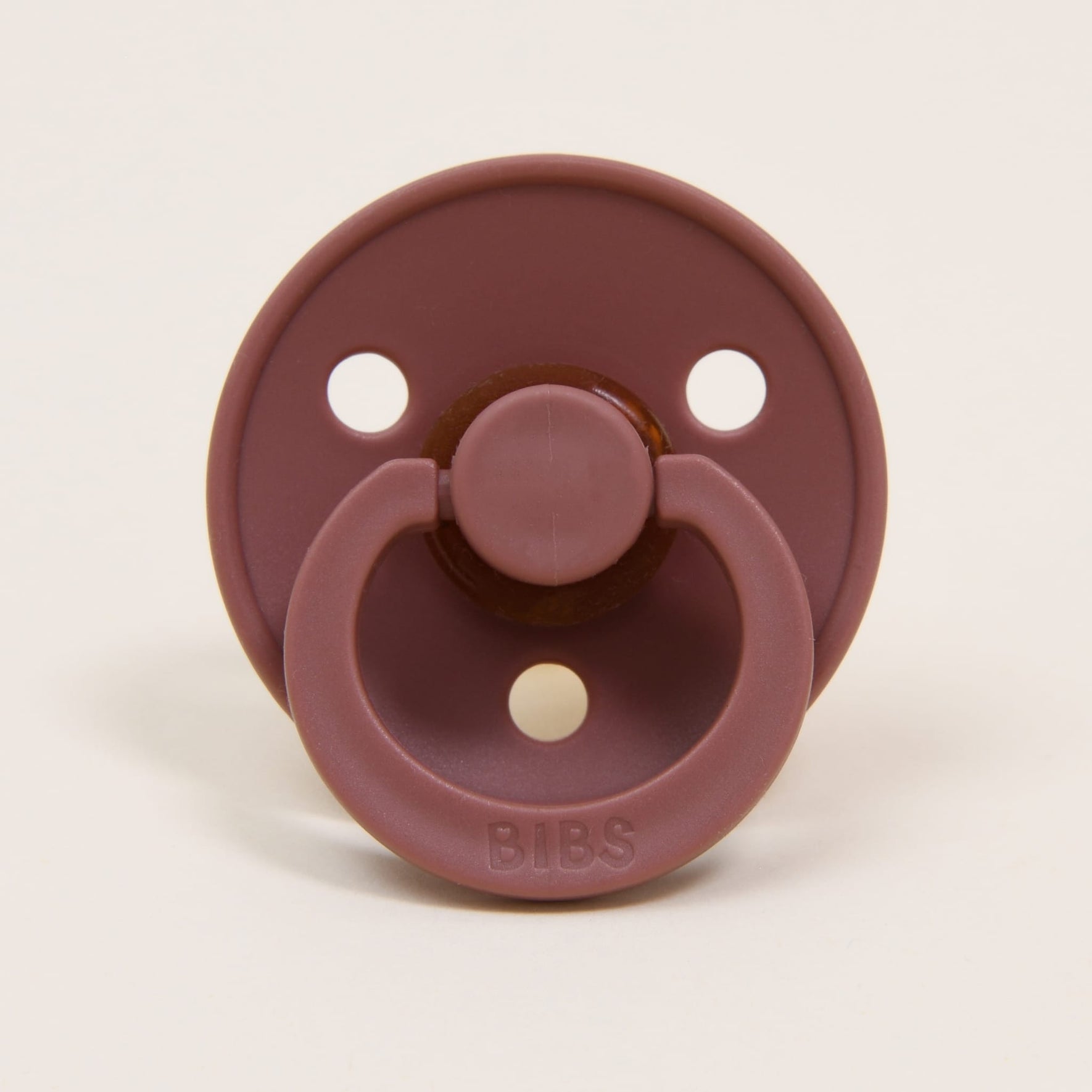 A Bibs Pacifier from the Woodchuck 2 Pack, crafted with natural rubber, is showcased against a plain background. Originating from Denmark, it features three ventilation holes, a round shield, and a pull handle—perfect for helping babies self-soothe.