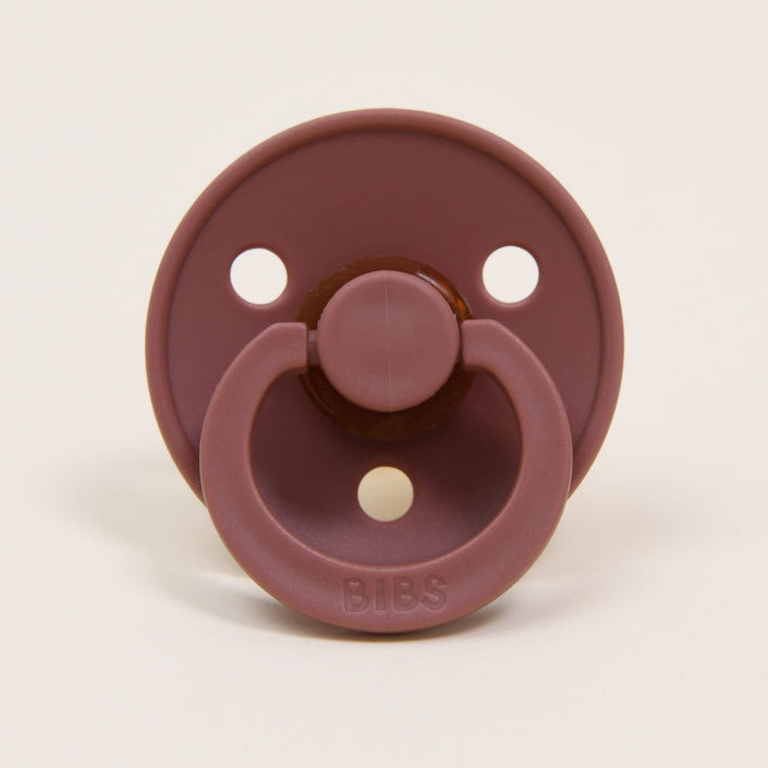 A Bibs Pacifier from the Woodchuck 2 Pack, crafted with natural rubber, is showcased against a plain background. Originating from Denmark, it features three ventilation holes, a round shield, and a pull handle—perfect for helping babies self-soothe.