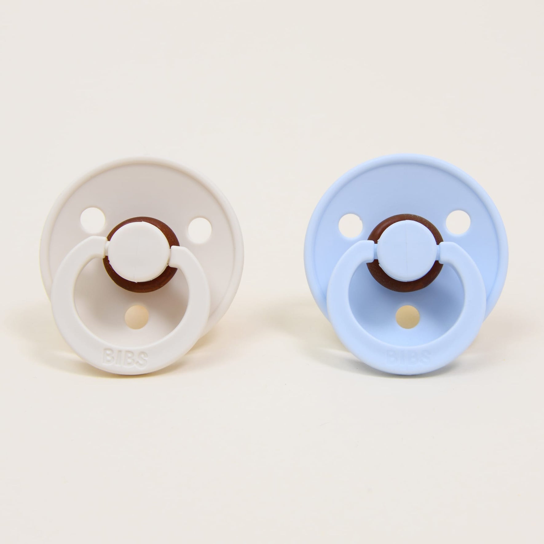 Photo of two pacifiers in two different colors: ivory and baby blue