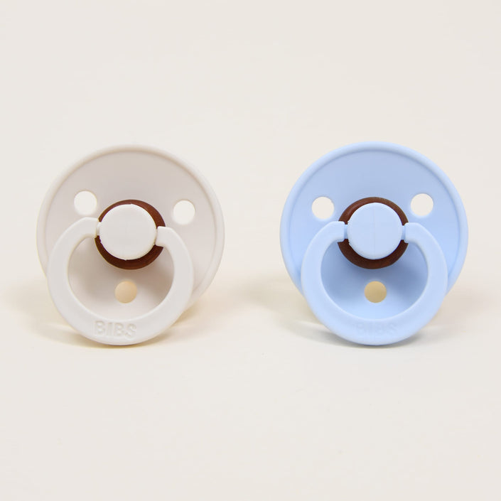 Photo of two pacifiers in two different colors: ivory and baby blue