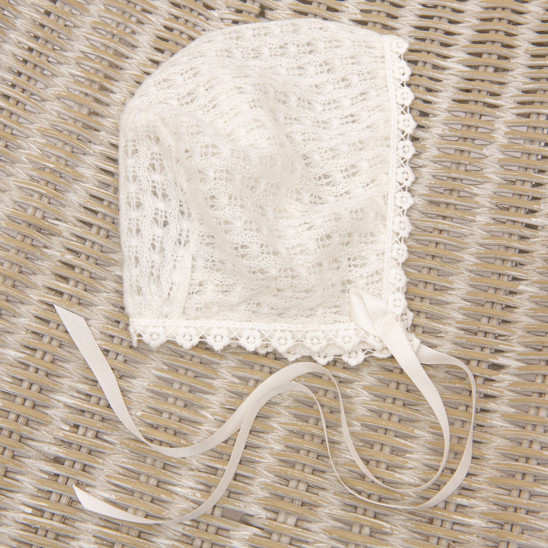 Close-up of the Ella christening bonnet with light ivory cotton lace trim and silk ribbon ties.