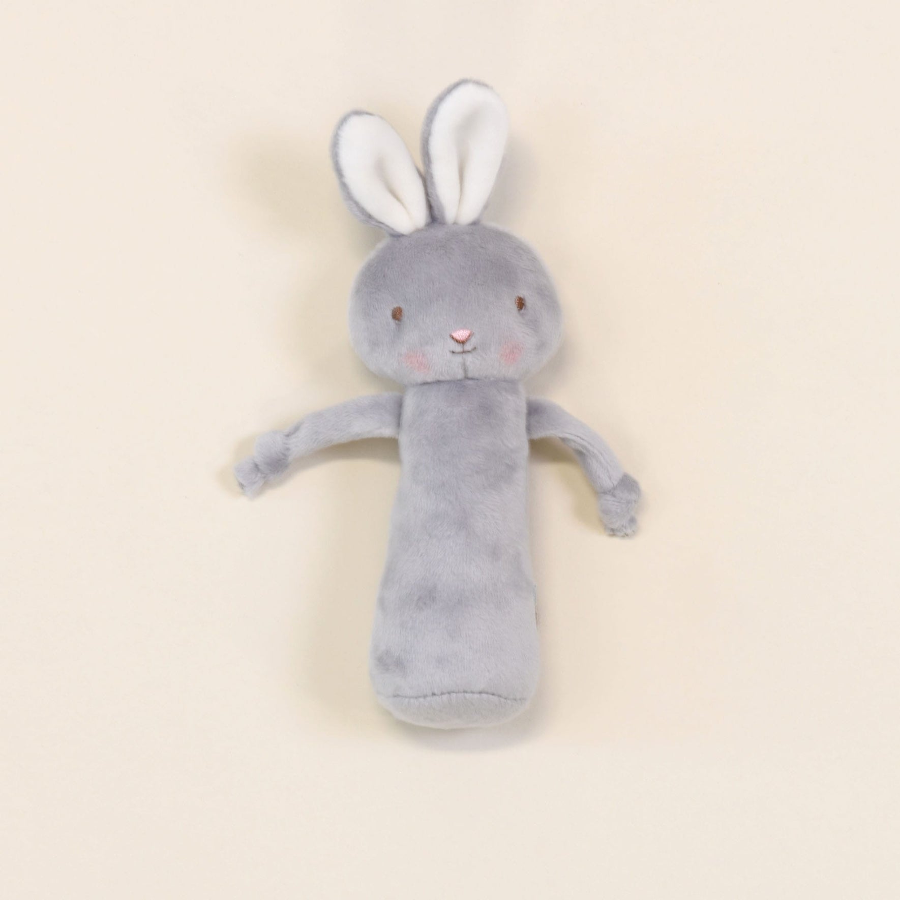 The Friendly Chime Rattle is a cozy, gray plush rabbit toy featuring long ears and delicate embroidered details. Its uncomplicated face and soft pink cheeks lie against a light beige backdrop, making it both a comforting companion and a velour chime rattle that’s perfectly safe for babies to cuddle endlessly.