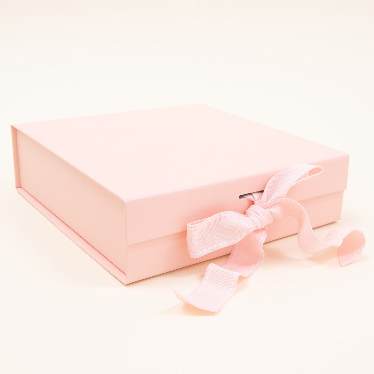 A closed, small gift box with a matching bow from Baby Beau & Belle provides a charming keepsake gift against a plain, pale background. Its light pink color enhances its appeal.