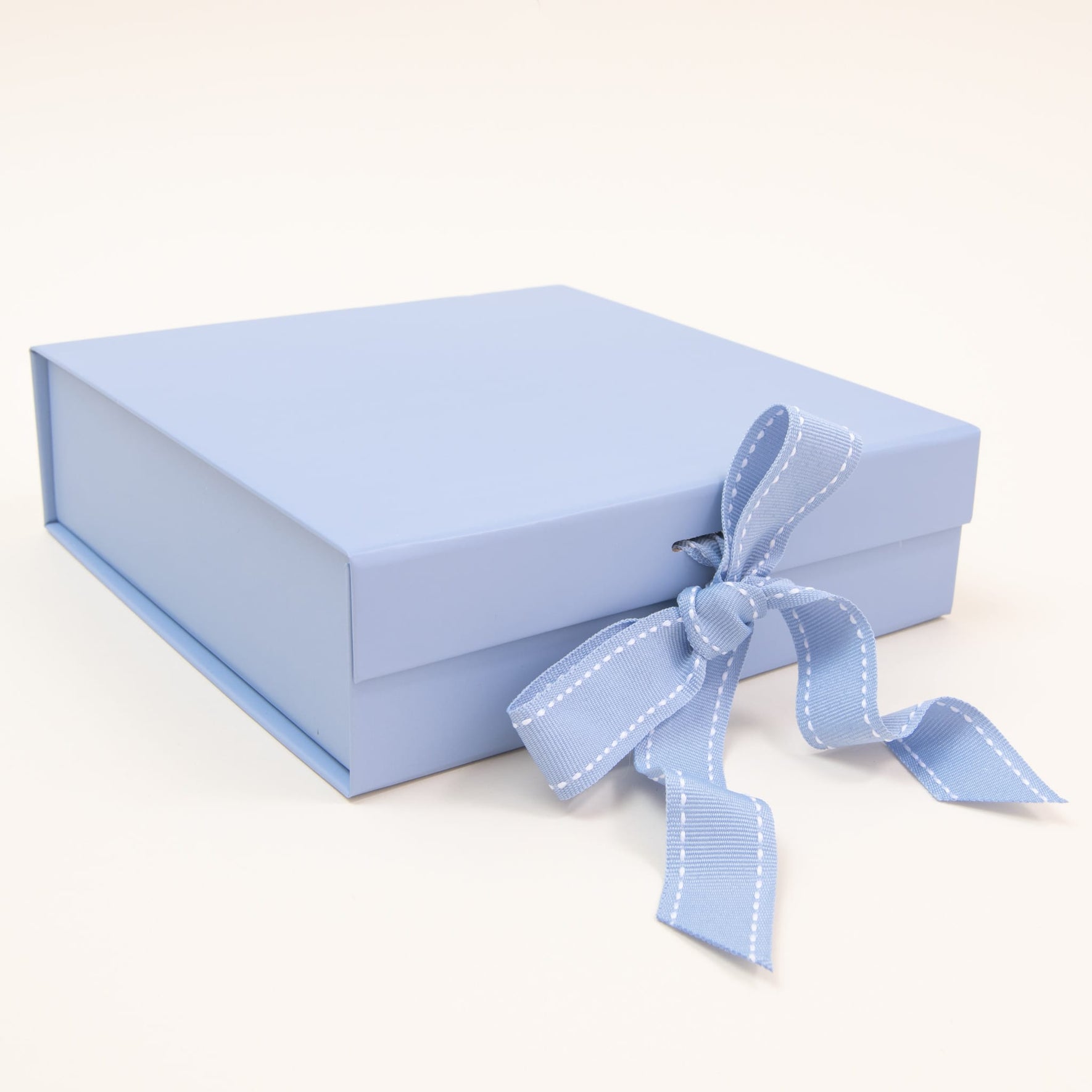 The "Gift Wrap | Small Gift Box with Bow" in a closed, light blue design, gracefully adorned with a matching ribbon tied into a bow, rests elegantly on a neutral backdrop.