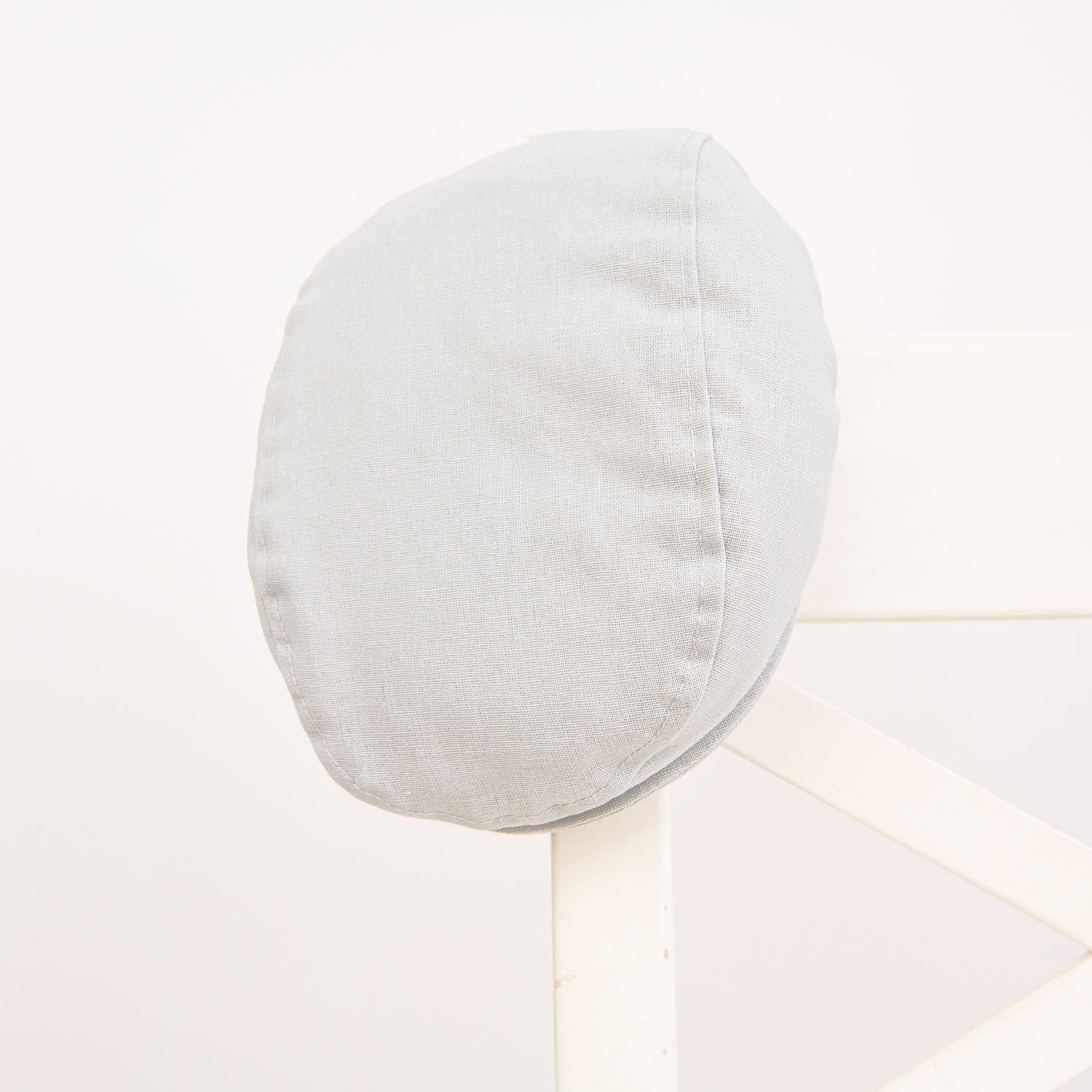 Flat lay photo of the Grayson Linen Newsboy Cap. The hat is made from a linen/cotton blend in grey with a soft elastic band around the back.