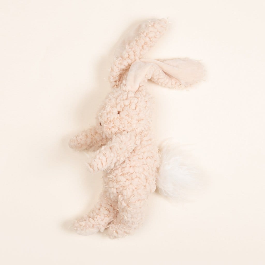 Flat lay photo of a super soft bunny stuffed animal made with warm almond scraggly fur body with embroidered face