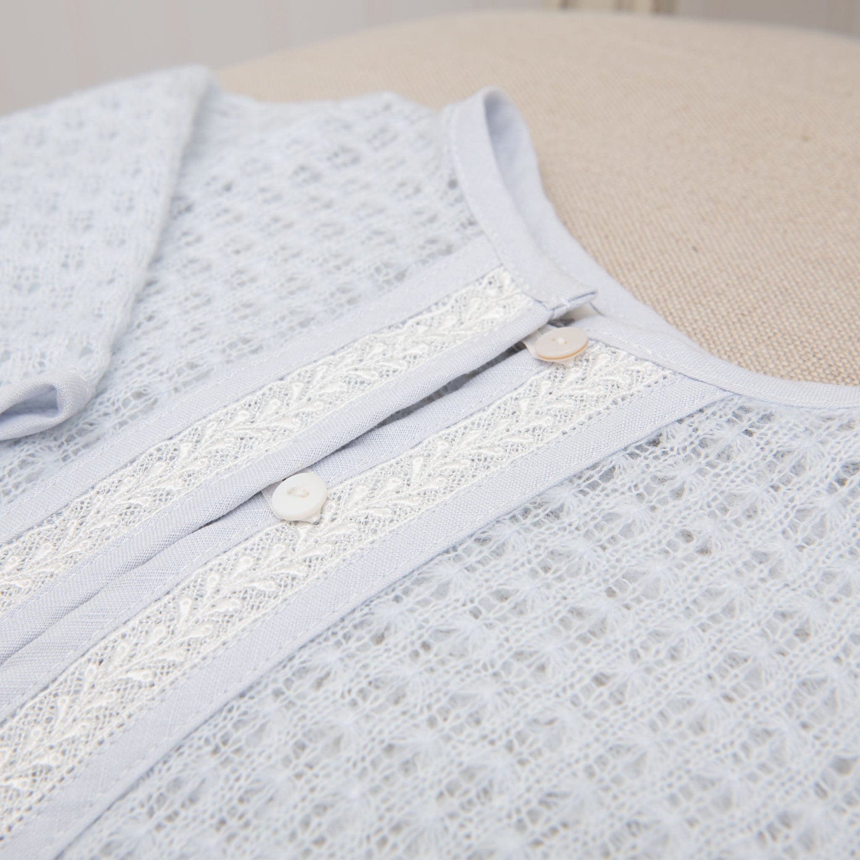Close-up of the blue knit christening sweater on a flat display, focusing on the delicate lace embroidery and soft knit design.