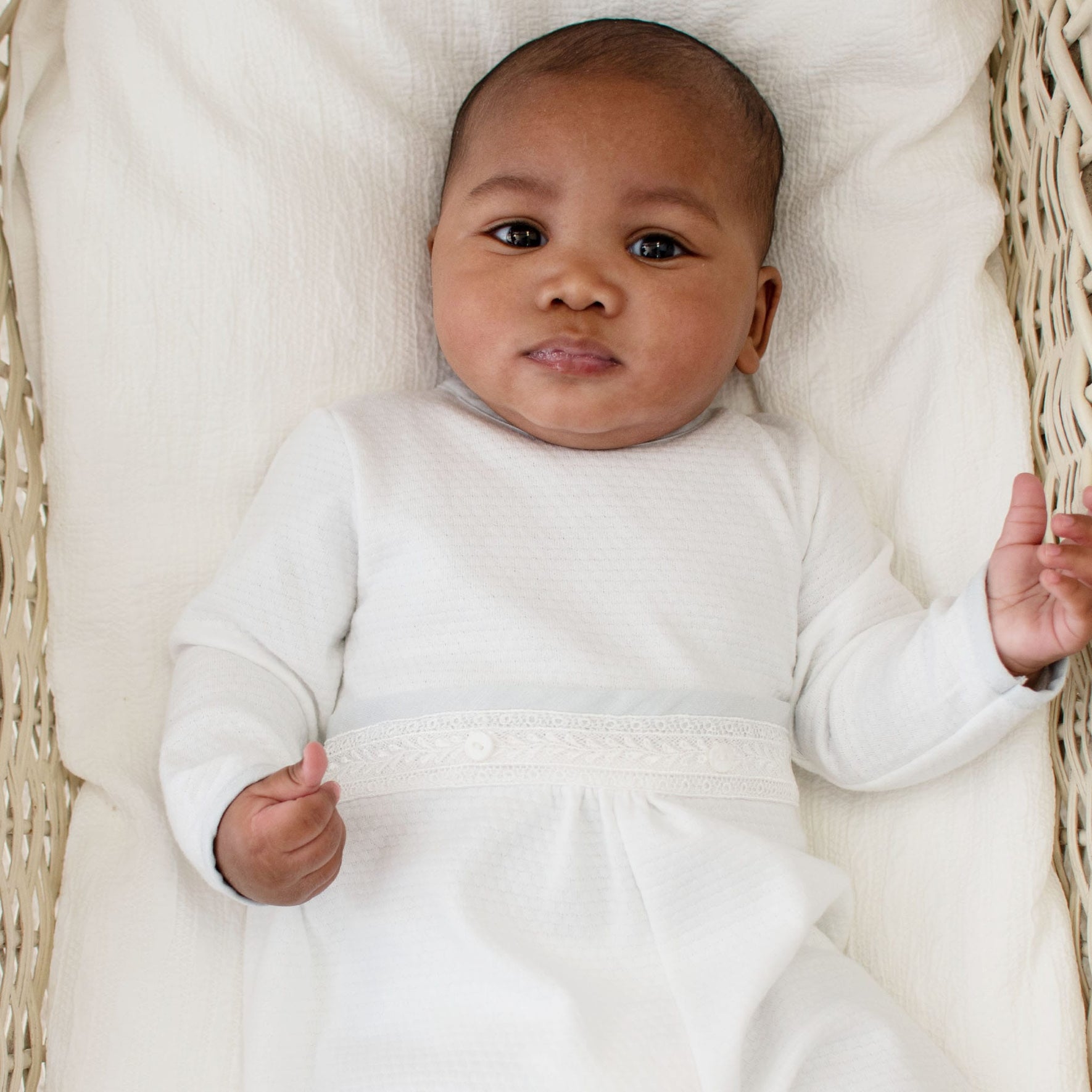 Infant in the Harrison Long Sleeve Christening Romper, lying comfortably and highlighting the elegant white fabric and embroidery.