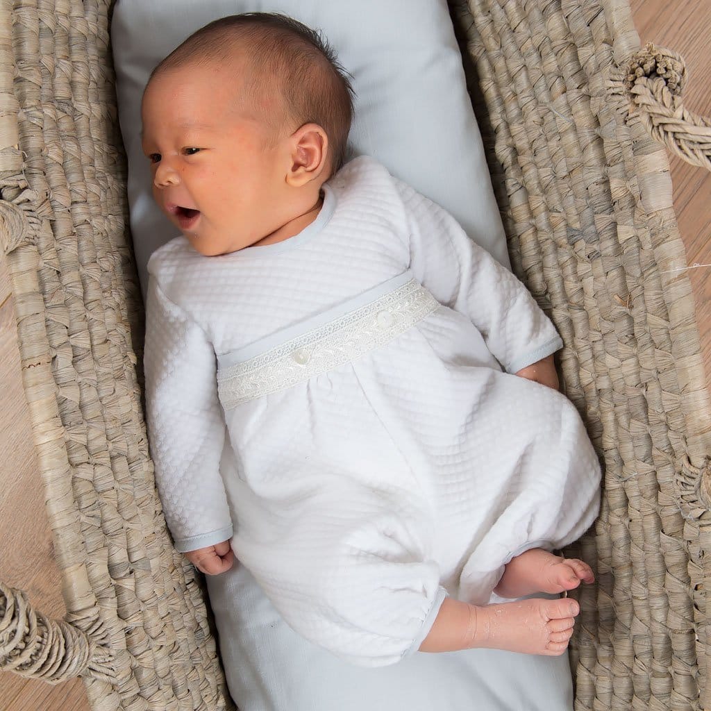 A newborn baby in the Harrison Newborn Romper, lying in a basket, perfect for christening day or special occasions.