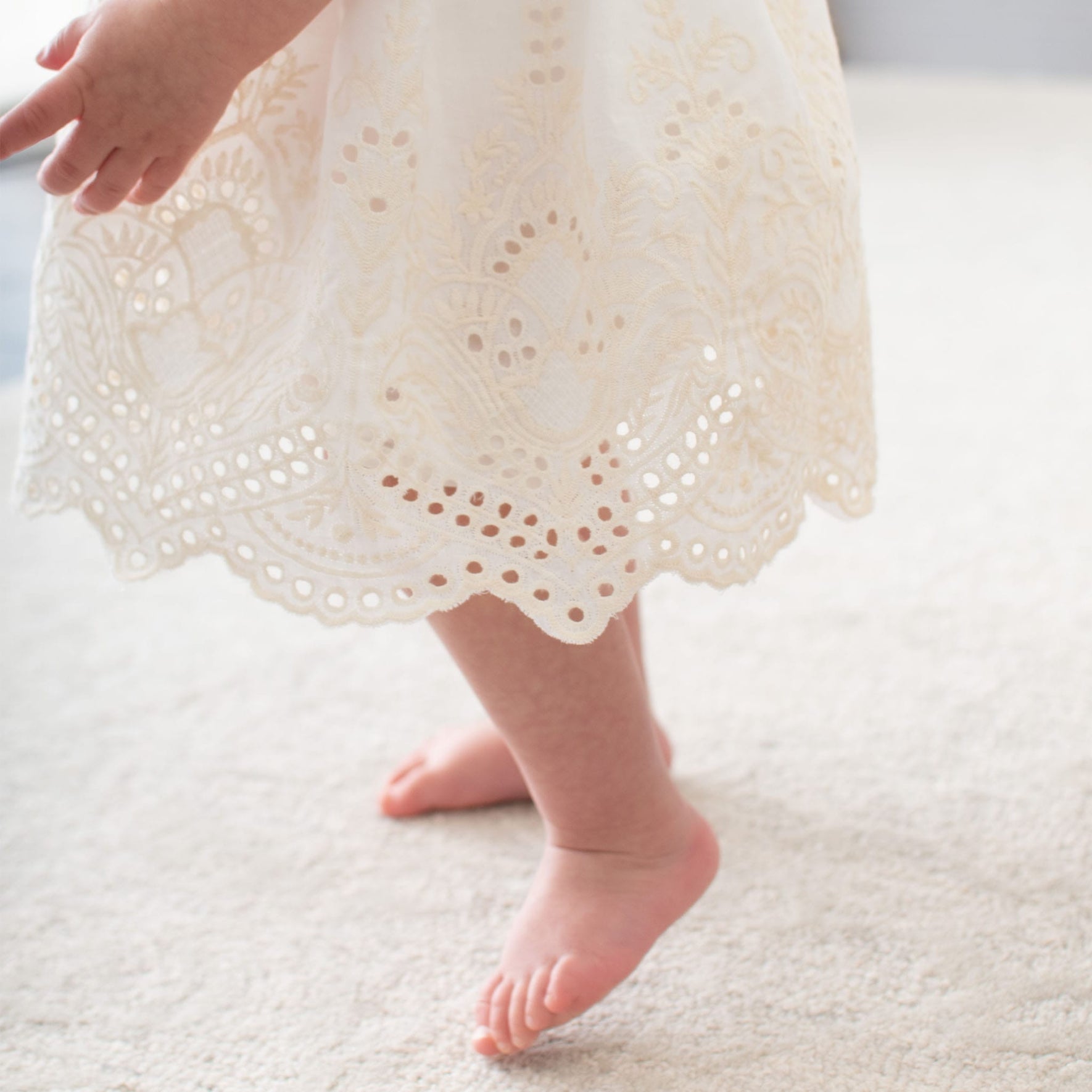 Detail of a baby wearing the ivory Ingrid Romper Dress skirt