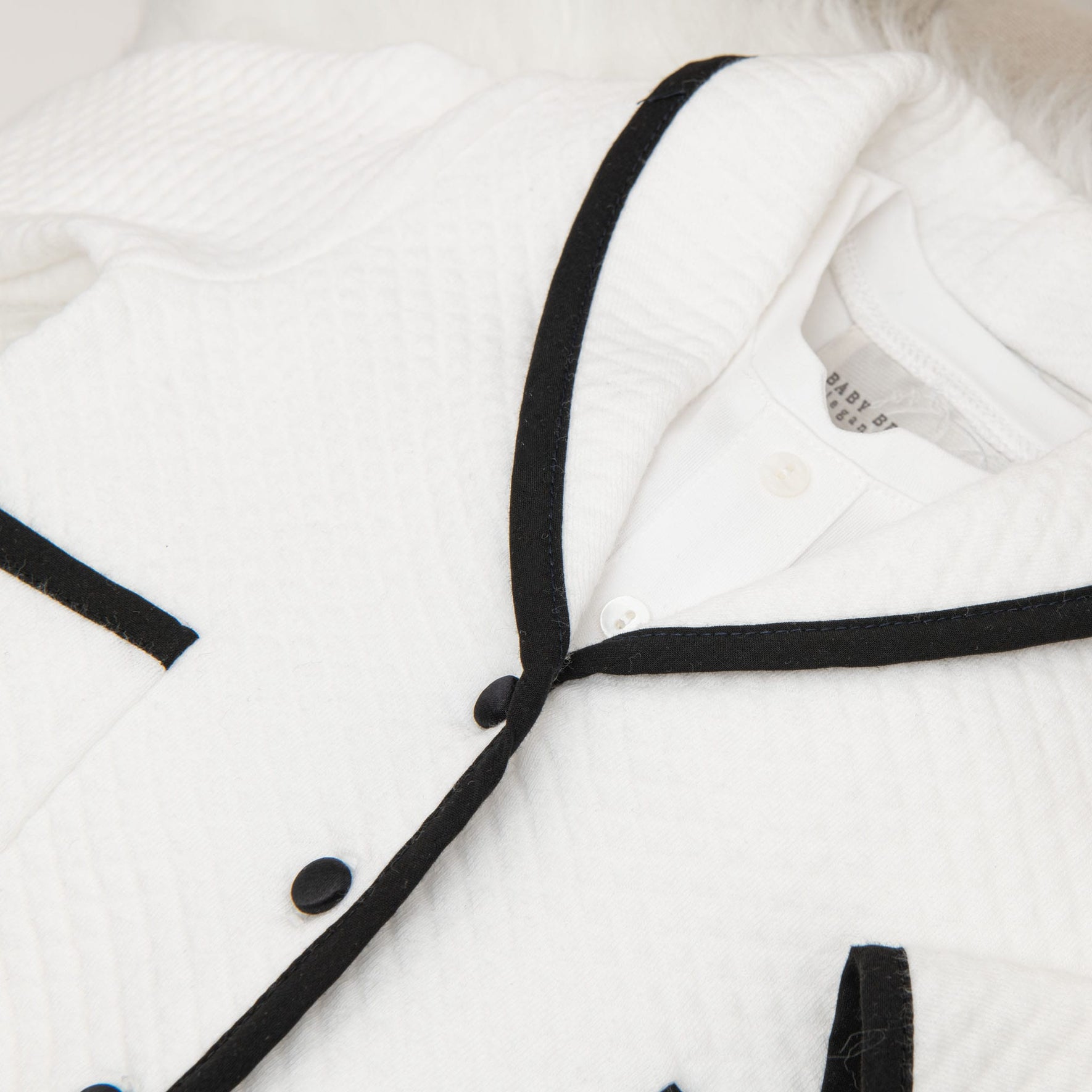 A close-up of the jacket from the James 3-Piece Suit, showing the fine quilted texture, black trim, and brand label inside the collar.