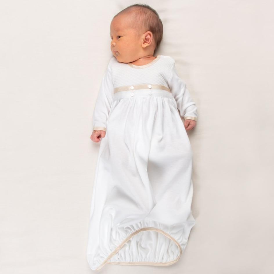 Newborn baby boy wearing the Liam Cotton Newborn Gown crafted from soft white pima cotton, ivory quilted cotton bodice, and detailed with silk trim in a shade of champagne